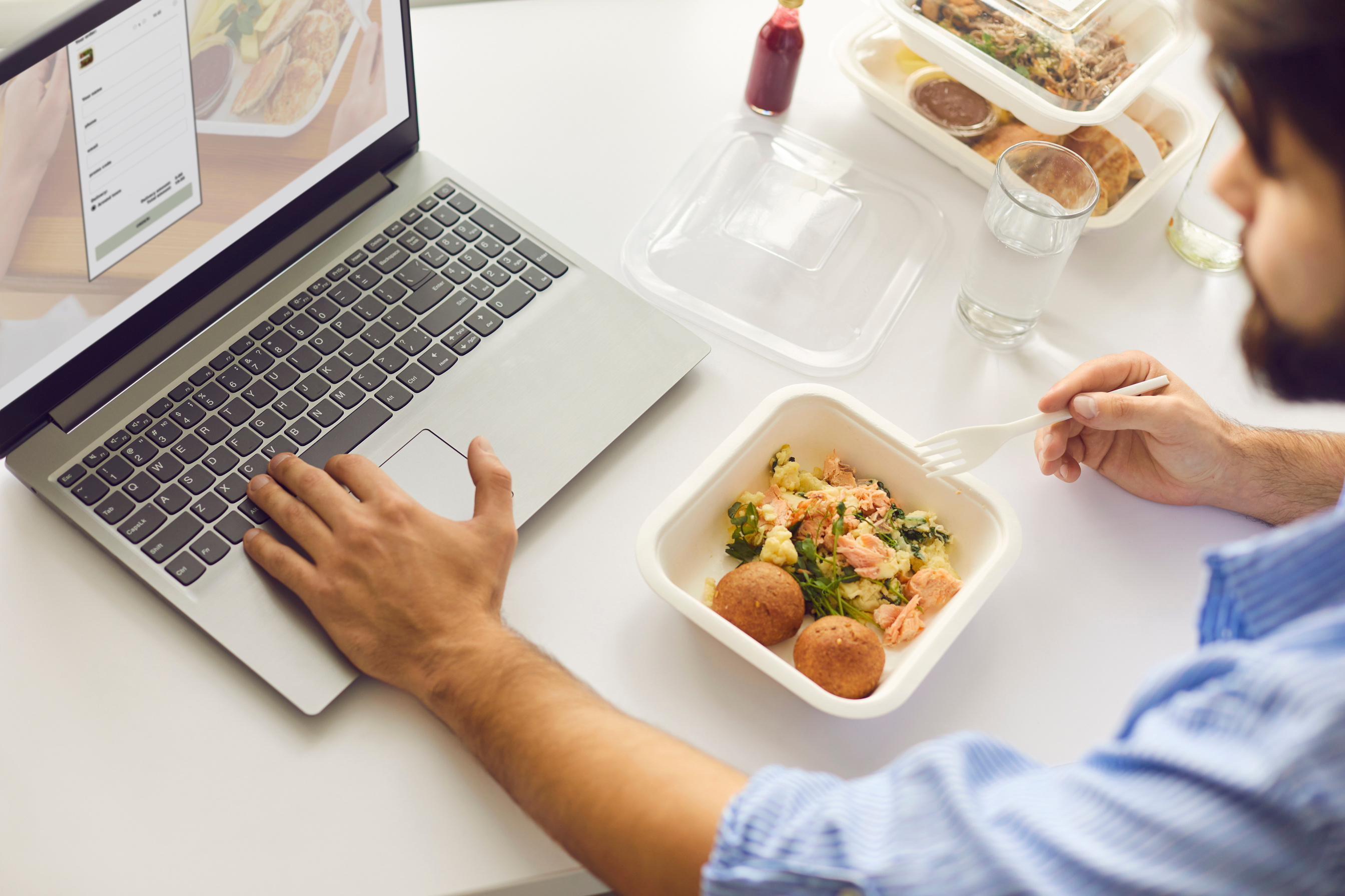 Man Having Lunch Break in Office, Eating Takeaway Meal and Signing up for Food Delivery Website